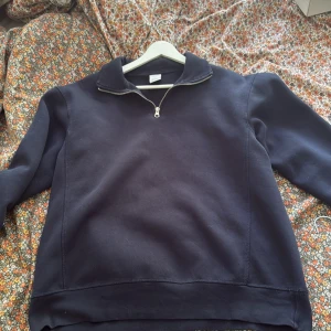 Mörkblå sweatshirt med half zip - Säljer en mörkblå sweatshirt från Fruit of the Loom med half zip och hög krage. Tröjan har långärmade och är gjord i mjuk bomullsmix, perfekt för chill dagar. Enkel och stilren design som funkar till jeans eller mjukisbyxor.