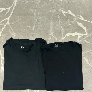 3 pack Svarta t-shirts från 157, Basic You & Low Vision - Tre svarta t-shirts, två med rund hals från 157 och Basic You, samt en från Low Vision med diskret ribbad struktur och randigt foder vid halsen. Alla har klassisk passform och är kortärmade, perfekta för en clean och enkel stil.