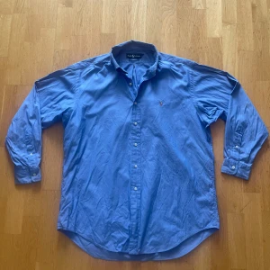 Blå skjorta från Ralph Lauren strl L  - Hej, säljer en klassisk samt fräsch skjorta från Ralph Lauren. Skick 9/10, använd ett fåtal gånger. Färg- ljusblå. Strl L, passar för en som är emellan 185-195. Inga defekter! Öppen för att diskutera priset! 