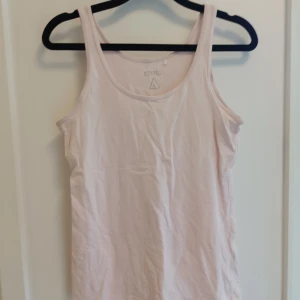 Ljusrosa linnetopp från Etirel - En enkel och fräsch ljusrosa linnetopp från Etirel. Toppen är ärmlös med klassisk rund halsringning och tillverkad i mjuk bomull, perfekt för varma dagar eller som lager under en hoodie.