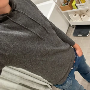 Merinoull hoodie - En stilren merinoull hoddie i mörkgrå färg. Tröjan har ett litet hål (slide 3) men är inget som märks av. Jag på bilden är 176 cm och väger 63 kg Tveka inte på att höra av er!