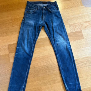 Blåa tiger of Sweden jeans med slitningar och skön wash W28 L32 - Säljer ett par blå slim jeans med snygga slitningar och tvättade detaljer.  dragkedja och knapp framtill. W28 L32