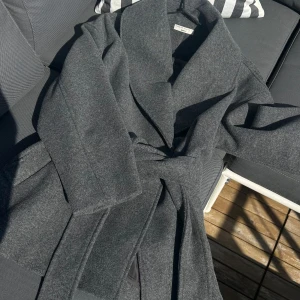 Grå omlott kappa med bälte - Snygg grå kappa från Gina Tricot i strl xs men funkar lika bra på någon med s. Använts 1 gång sedan inköp. 450 kr