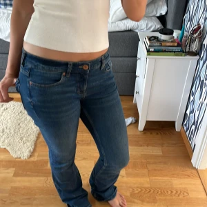 Blå bootcut jeans med låg midja - Säljer ett par klassiska blå jeans med bootcut-modell och låg midja. Snygg passform som sitter tajt upptill och släpper vid vaden. Perfekta till sneakers eller boots. Slitningar längst ner annars i toppskick. Nypris 599kr