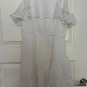 Vit prickig volangklänning Lindex - Supersöt vit klänning från Lindex med tunna axelband och offshoulder-volanger. Prickigt mönster och flera lager med volanger ger en romantisk vibe. Perfekt för sommarens alla tillfällen! Lätt och luftig polyester som känns skön mot huden.