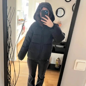 Mörkblå vinterjacka från Tommy Hilfiger - Mörkblå pufferjacka från Tommy Hilfiger med huva och dragkedja framtill. Jackan är vadderad och håller dig varm. Jackan är knappt använd pga storlek. Köpt för 2200kr