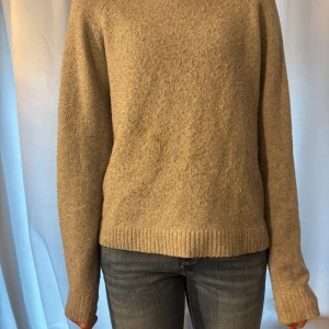 Beige stickad tröja med rund hals - Enkel och stilren beige stickad tröja med rund hals och långa ärmar. Tröjan har ribbade muddar vid ärmslut och nederkant. Passar dig som gillar en klassisk och avslappnad look. Ganska nopprig, diskuterbart pris.