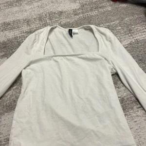 Vit långärmad topp från Divided - Snygg vit långärmad topp från Divided med fyrkantig urringning. Enkel och stilren design som passar perfekt till jeans eller kjol. Mjuk och skön i bomullsmaterial, perfekt för dig som gillar minimalistisk stil.