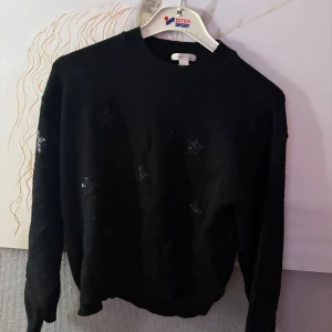 Svart stickad tröja Gina Tricot - Svart stickad tröja från Gina Tricot i storlek 158/164. Tröjan har rund halsringning, långa ärmar och diskreta paljettdekorationer framtill. Perfekt för dig som gillar en enkel men ändå lite glittrig look.