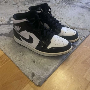 Nike Air Jordan 1 carbon sneakers - Äkta och precis som nya! Snygga Nike Air Jordan 1 sneakers i svart och vitt med klassisk hög siluett. Skorna har svart snörning, vit bas och svarta detaljer i glansigt skinn. Ikonisk vinge-logga på sidan och svart swoosh. Perfekta för dig som gillar streetstyle och vill sticka ut. Ord pris : 3799kr