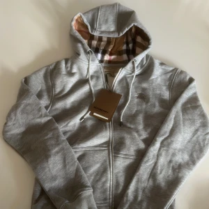 Grå hoodie från Burberry med dragkedja - Säljer en grå hoodie från Burberry i storlek M. Säljer för den inte passar mig. Passar både S och M. Kan gå ner i pris vid snabb lätt affär. 