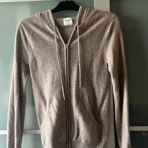 Beige cashmere hoodie från John Henric - Mjuk och lyxig beige hoodie från John Henric i 100% cashmer från NK i Göteborg . Tröjan har dragkedja framtill, snörning vid huvan och två fickor. Långärmad med ribbade muddar och avslappnad passform. Ny pris 2750 mitt pris: 1695! Hör av er vid minsta lilla fråga! Nästan aldrig använts 