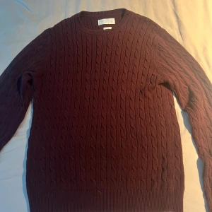 Vinröd stickad tröja These Glory Days - Säljer en vinröd stickad tröja från These Glory Days i storlek L men passar även M. Tröjan har ett klassiskt kabelstickat mönster, rund hals och långa ärmar. Perfekt för dig som gillar stilrena och tidlösa plagg med lite extra struktur. Passar dig som vill ha en chill och snygg look.