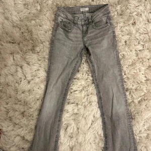 Grå bootcut jeans med slitning - Snygga grå jeans med bootcut-modell och lätt slitning. Klassisk femficksdesign och normal midja. Perfekta för dig som gillar en retro vibe och vill ha ett par jeans som sticker ut lite extra.