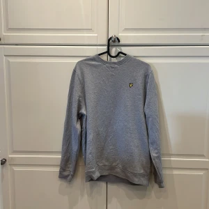 Grå sweatshirt från Lyle & Scott - Säljer en stilren grå sweatshirt från Lyle & Scott med deras ikoniska logga på bröstet. Passar dig som är 170-175. Säljer då den ej kommer till användning.