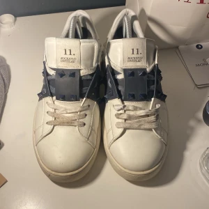 Valentino opens  - Snygga vita sneakers från Valentino med mörkblå. Perfekt till våran och sommaren. Använt i några månader. Tappat några spikar och inge box därav priset. Kommer ett extra par skor snöre och påsen som jag har visat i annonsen. Har byt ut skor snöre en gång därför har den inte den org. 