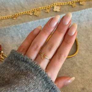 Guldfärgad ring med måne och stjärna - Elegant 18K guldfärgad ring från Glitter med en dekorativ måne och en liten stjärna. Perfekt för att ge en subtil men stilfull touch till din look. Ringen har en justerbar design för att passa olika storlekar (storlek 17 mm).
