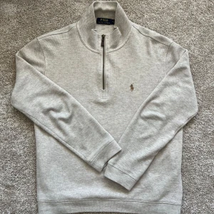 Beige half-zip från Polo Ralph Lauren - Säljer nu denna feta half-zip tröjan från Polo Ralph Lauren då den inte kommer till användning. Färgen ser lite grå ut på bilderna men den är beige. Hör gärna av er om ni har några frågor eller funderingar!