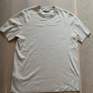 Beige t-shirt från mango - Säljer en stilren beige t-shirt från mango Den har en klassisk rund hals och korta ärmar, perfekt för en minimalistisk look. Passar till allt och är superbekväm. Perfekt basplagg för garderoben!