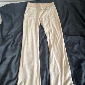 Beige mjukisbyxor från Juicy Couture - Säljer ett par bekväma beige mjukisbyxor från Juicy Couture. Byxorna har fickor fram och bak.  Dom har en liten fläck på benet men det syns knappt! Dessa är ute på fler sidor!!!