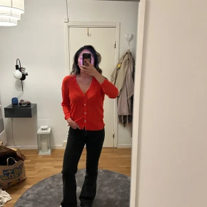 Röd kofta från Calvin Klein  - Säljer en snygg röd kofta från calvin Klein med v-ringning och knappar framtill. Koftan har långa ärmar i storlek S