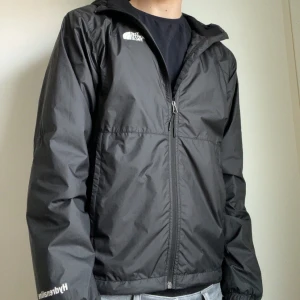 Svart vindjacka från The North Face - Säljer denna snygga svarta vindjacka/regnjacka från The North Face med dragkedja och huva i storlek S. Använd ett fåtal gånger och väl omhändertagen, lägg ett bud eller köp direkt!