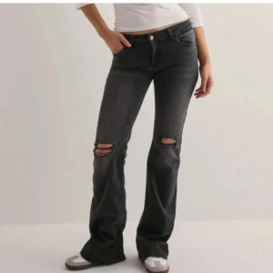 Svarta jeans med slitningar - Snygga svarta jeans med slitningar på knäna och broderade bakfickor. De har en bootcut-stil och är low-waisted. Taggar intakta