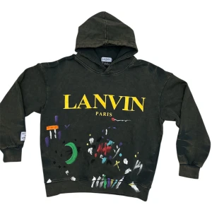 Lanvin hoodie  - Cool svart hoodie från Lanvin med färgglada abstrakta mönster och stor gul logotyp på framsidan. Den har en klassisk huva och ribbade muddar vid ärmslut och nederkant. Perfekt för en avslappnad stil.har tagit bort stringsen, mvh scandicfashion 
