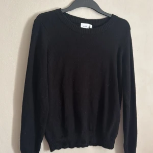 Svart tröja från Vila - Säljer en klassisk svart tröja från Vila. Tröjan har en rund halsringning och långa ärmar, perfekt för kyligare dagar. Den är enkel och stilren, vilket gör den lätt att matcha med olika outfits.