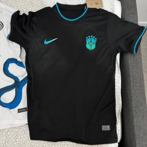 Fotbollströjor - Snygg vit och ljusblå fotbollströja från Nike med ett unikt mönster. Tröjan har korta ärmar och en modern design med logotypen 'digitalbits' på framsidan. Perfekt för fotbollsfans som vill sticka ut på planen eller läktaren.”INTRESSERAD AV ANDRA FOTBOLSTRÖJOR ELLER KITS BARA MEDDELA OSS SÅ LÖSER VI DE” Dessa är i Storlek L 
