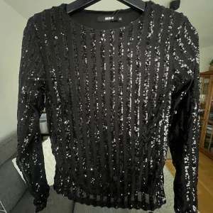 Svart paljettopp från Bik Bok  - Helt ny paljetttopp från Bik Bok i storlek XS med prislappen kvar. Säljer eftersom den är för liten för mig. Toppen har små axelvaddar och består av ett innertyg och ett tunt yttertyg med paljetter. 