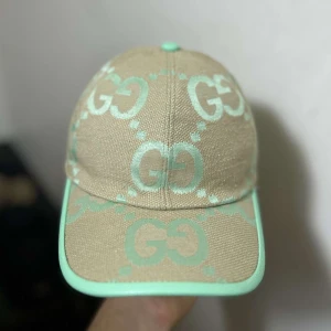Beige och mintgrön keps från Gucci - Snygg keps från Gucci i beige canvas med mintgröna GG-loggor och detaljer. Kepsen har böjd skärm och justerbart spänne bak i mintgrönt. Perfekt för dig som vill sticka ut med en exklusiv accessoar. Sommaren blir bättre med en mintgrön keps från Gucci😉🌞☀️