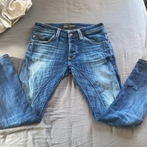 Blå jeans från Jack & Jones - Säljer ett par klassiska blå jeans från Jack & Jones med fem fickor och snygg fadening. Jeansen har slim passform, perfekt till vardags. Stängs med knappar. Pris kan sänkas vid snabb affär mvh August 
