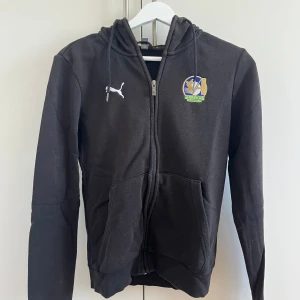 Svart hoodie från Puma med klubbmärke - Svart hoodie från Puma med Abbekås golfklubb logga. Använd men fortfarande i bra skick. Väldigt bekväm. 