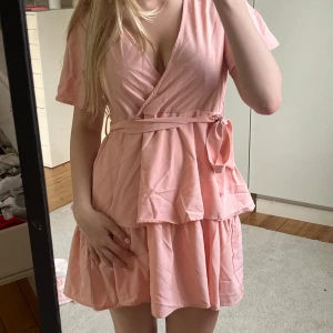 Rosa omlottklänning från SHEIN! - Supersöt ljusrosa kortklänning från med omlottmodell, volangdetaljer och knytband i midjan. Från shein så säljer billigt. Använd 1 gång på ett bröllop🥰strl xs. Funkar för s också. 