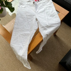 Vita jeans från edc - Snygga vita jeans från edc. Byxorna har tajt  passform, raka ben och är tillverkade i bomull (98%) och elestan (2%). Modellen är capri som når precis nedanför knät. Resår i midjan. Fickor, knapp och gylf fram är endast dekoration. Två fickor bak. Storlek 36. 