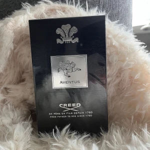 Creed Aventus 100ml parfym - Lyxig parfym Creed Aventus i svart och silver kartong med ikonisk logga och ryttare. Flaskan rymmer 100 ml och är känd för sin exklusiva doft och eleganta design. Perfekt för dig som vill sticka ut med en klassisk och tidlös parfym. Parfymen är helt ny med plasten fortfarande kvar!! Jag säljer pågrund av doftalergi.