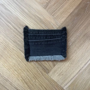 Jeans plånbok  - Fin jeans plånbok med lite stretchigare tyg och fransiga kanter, har tre fak för kort och är i normal storlek.