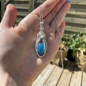 Silverberlock med blå sten och en en liten bergskristall  - Hänget har snirkliga detaljer och en cool, bohemisk vibe. Passar till de allra flesta kedjor. Perfekt för att lyfta vilken outfit som helst.