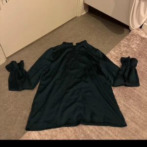 Grön blus - Grön blus med långa ärmar och volangdetalj längst ner på ärmarna. Stilren men med en romantisk touch. Superfin till både vardag och fest! Skönt material och normal passform. Endast använd ett fåtal gånger – i mycket fint skick 💚