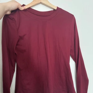 Vinröd långärmad tröja i bomull - Enkel och stilren vinröd långärmad tröja i mjuk bomull. Perfekt basplagg med rund halsringning och normal passform. Passar till allt och är lätt att matcha med andra plagg.
