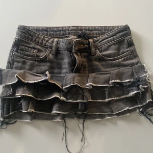 Svart volangkjol i jeans från Weekday - superfin svart/grå jeanskjol med volanger. kjolen är ursprungligen ett par jeans från weekday i storlek w24/L32. ej använd så många gånger därför säljer jag den. skriv för mått privat