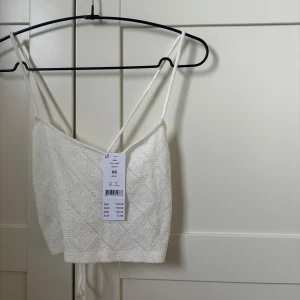 Vit croppad linnetopp med snörning - Superfin croppad linnetopp i offwhite med tunna axelband som korsas i ryggen och knyts. Den är så fin i ryggen och jättegulligt material 🥰 passar jättebra till en långkjol. Helt ny med prislapp på storlek xs. Köpt för 179 men säljer för 70!