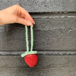 Handvirkad jordgubb-nyckelring  - Supersöt liten virkad jordgubbe med röd botten och ljusgröna detaljer. Perfekt som accessoar / nyckelring. Jordgubben har två gröna handtag och är lätt att fästa på exempelvis en väska eller nyckel. Köp med väska = 50kr.