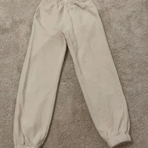 Beiga mjukisbyxor från Gina Tricot XS - Beiga mjukisbyxor från Gina Tricot i modellen Basically Basics. De har resår i midjan och vid bensluten, samt sidfickor. Mjukt material i bomullsblandning, perfekta för chill dagar. Enkel och clean look som passar till allt.