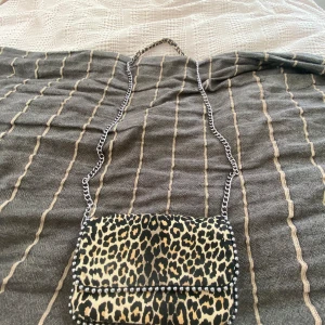 Leopardmönstrad axelväska från Zara - Cool axelväska från Zara med leopardmönster i svart och beige. Väskan har silverfärgad kedjerem och nitar längs kanterna. Insidan har ett fack med dragkedja och magnetlås. Perfekt för att lyfta vilken outfit som helst. Säljer på den på vinted också och heter verisjohansson där också💘💘