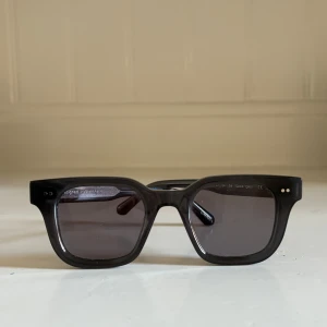 Chimi 04 mörkgrå - Snygga svarta solglasögon från Chimi med fyrkantig form och mörka glas. Ramen är tjock och stilren, perfekt för dig som vill ha en modern och clean look. Kommer med originalfodral. Ser lite mörkare ut på sista bilden, men i ljus är de ljusare