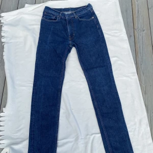  jeans straight fit - Klassiska jeans i mörkblå denim med raka ben och kontrastsömmar. Jeansen har fem fickor och en tidlös straight fit som alltid funkar. Perfekta för dig som gillar en clean och enkel look.