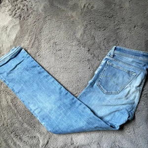 Ljusblå  jeans från Jacob Cohen - Säljer ett par ljusblå skinny jeans från Jacob Cohen med klassisk femficksdesign och snygga slitningar. Jeansen har låg midja och är tillverkade i mjukt bomullstyg med stretch för extra komfort. Perfekta för dig som gillar en smal passform och avslappnad look.