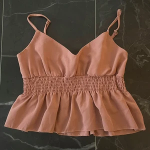 Rosa topp - Kort rosa ropp med volanger. Som ny endast använd någon gång!